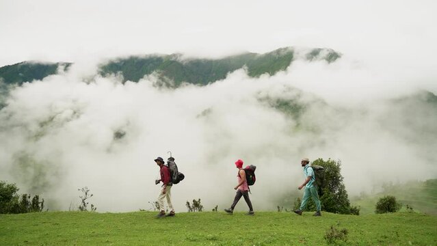 Group of young friends hiking in countryside. Three men walking by hiking trail. Three Friends Travel and Adventure Concept in Bedni bugyal, Uttarakand, India.