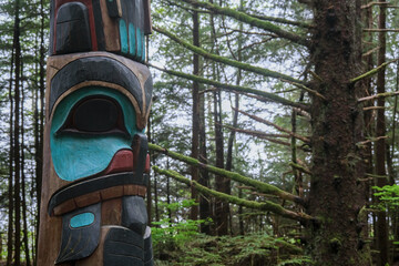 Tlingit totem poles and lush woods tree nature landscape scenery in Sitka Historical Park hiking trails with creeks, green bushes and vegetation in magic fairytale environment Baranof Island - obrazy, fototapety, plakaty