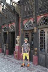 Ancient architecture, old building facade, house and tourist child, cute boy, kid in Lahore, Pakistan. Lahore landmark, old monument, interior. Wooden architecture. Cooco's den cafe, old restaurant