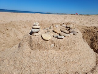 Fototapeta na wymiar Château de sable sur la plage avec des galets