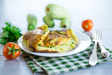 Fried omelet with zucchini, on a wooden table.