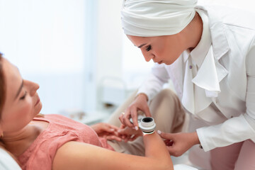 The dermatologist examines the moles or acne of the patient with a dermatoscope. Prevention of...