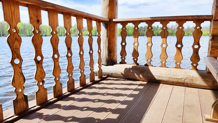 Wooden carved railings and water in a river or lake on a sunny summer or spring day. Natural landscape. Background and pattern. Handmade