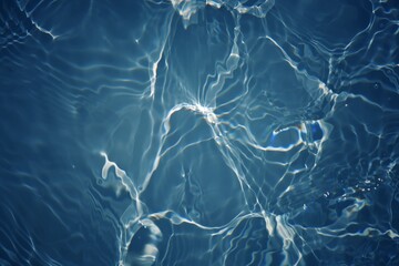 Blue water with ripples on the surface. Defocus blurred transparent blue colored clear calm water surface texture with splashes and bubbles. Water waves with shining pattern texture background.