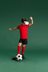 Fototapeta na wymiar Online games. Little boy, child wearing vr glasses and playing football against green studio background. Concept of childhood, kids emotions, sportive lifestyle, action, hobby, ad