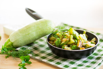 Sliced zucchini fried with onions and herbs in a frying pan