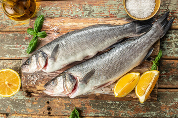 Fresh raw sea bass on a wooden background. banner, menu, recipe top view