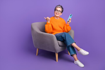 Full body size photo of old lady direct finger looking interested novelty phone website discounts isolated on purple color background