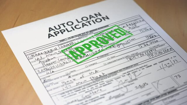 A closeup view of a automobile loan application getting approved. Data on form is fictional.  	