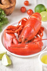 whole boiled lobster on a white plate with lime slices

