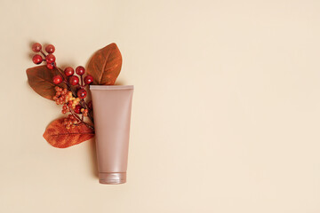 Cosmetic Cream tube mockup with autumn leaves on Beige color background. Natural skincare beauty...