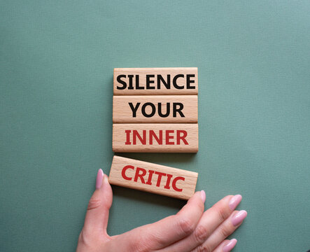Silence your inner critic symbol. Wooden blocks with words Silence your inner critic. Beautiful grey green background. Businessman hand. Business and Silence your inner critic concept. Copy space.
