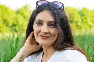 Portrait of a 35-year-old brunette woman looking at the camera smiling in nature.