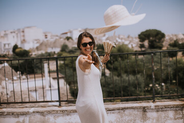 A young woman in a white dress throw hat during tourist visit in Alborebello, Italy