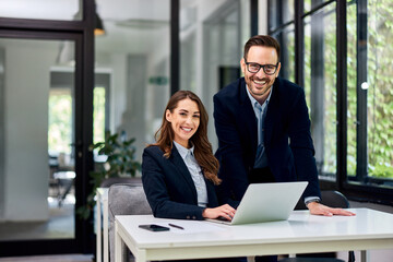 Portrait of a male boss and a female employee with a laptop at the office.