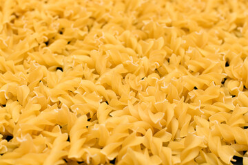Uncooed Fusilli Pasta - Background. Texture of Bright Golden Dry Macaroni
