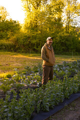 A young farmer hipster stands confidently in a lush green field, exuding a sense of connection to nature and a modern aesthetic. 