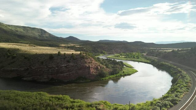 Back away from Colorado River by train tracks under red rock dry desert mesas in summer