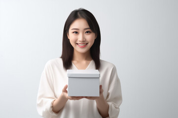 Fototapeta premium In front of view portrait of woman wearing T-shirt standing with carton box and looking at camera with sweet smile isolated on white gray background. Generative AI.