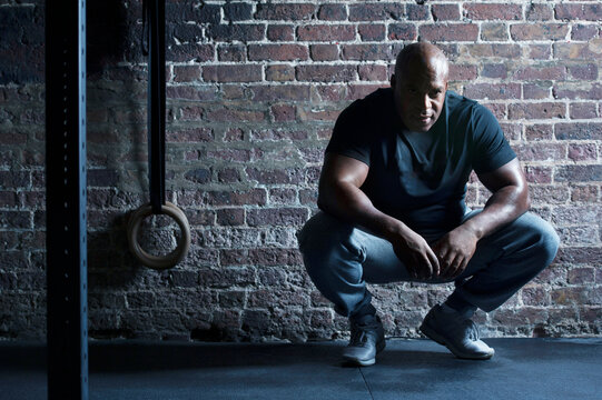 Mid adult man crouching at brick wall