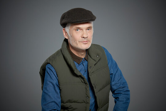 Portrait of mature man wearing vest and flat cap.