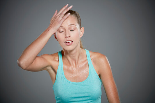Portrait of sweating young woman with her hand on her head.