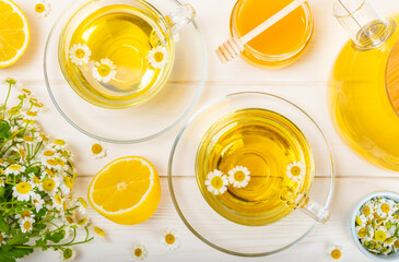 Chamomile tea on a white table. Delicious tonic, soothing and relaxing chamomile tea with chamomile flowers, honey and lemon. Herbal tea for immunity. Close-up.Place for text.Copy space.