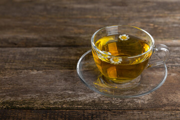 Chamomile tea on a brown table. Delicious tonic, soothing and relaxing chamomile tea with chamomile flowers, honey and lemon. Herbal tea for immunity. Close-up.Place for text.Copy space.