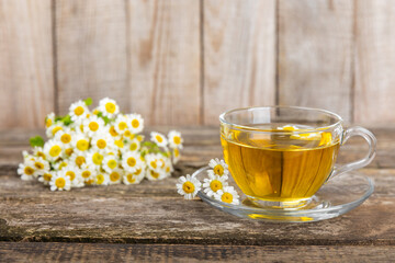 Chamomile tea on a brown table. Delicious tonic, soothing and relaxing chamomile tea with chamomile flowers, honey and lemon. Herbal tea for immunity. Close-up.Place for text.Copy space.