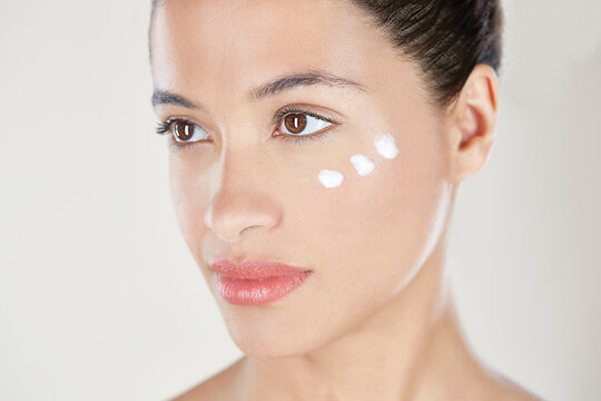 Woman with face cream on cheek.