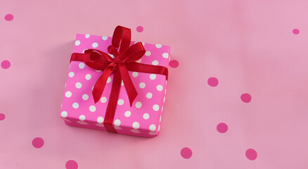 pink gift box with white dots with pink ribbon on pastel pink background in high resolution and sharpness