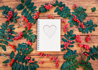 Heart shape spiral notebook with autumn decoration berries and leaves. Back to school, study, fall background.
