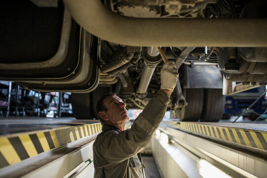 Mechanic in pit beneath truck