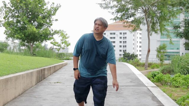 Asian fat man exercising outdoors on the roof of the building, he is tired and the weather is very hot. Heat stroke. Health care.
