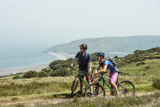 Couple wearing bicycle helmets on hill in Porlock Weir, England