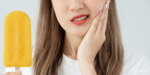 Asian woman feel sensitive teeth after eating ice cream, female suffer tooth, decay problems,...