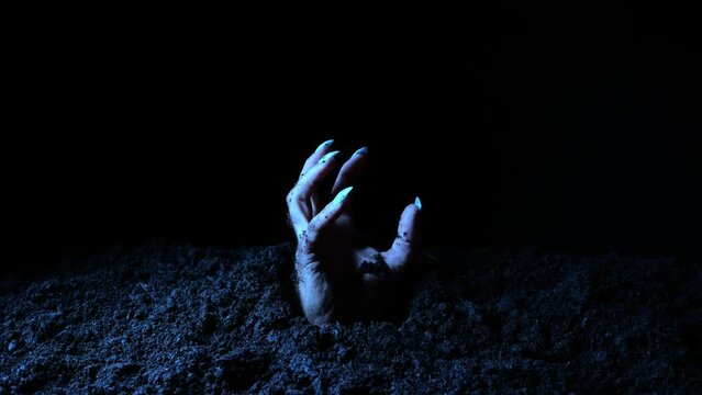 The hand of the deceased comes out of the soil in the cemetery.