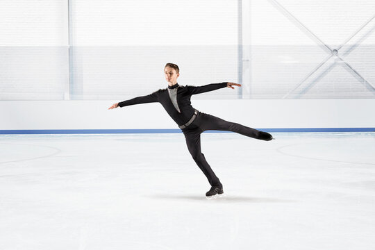 Young man figure skating on ice rink