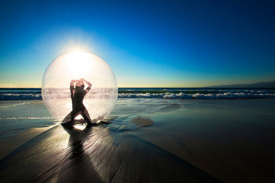 Woman Doing Yoga In Ball On Beach During Sunset