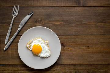 One fried egg on plate, top view. Breakfast background