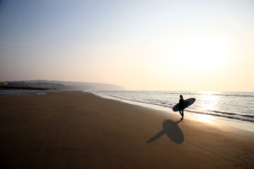 Silhouette of woman with surfboard on beach