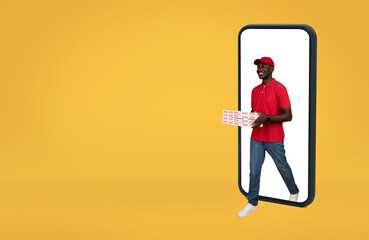 Happy young african american delivery man in uniform coming out of smartphone with blank screen...