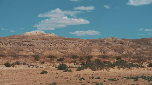 This stock video shows a sandy canyon on a sunny summer day. Above the canyon, white clouds float in the blue sky. This video will decorate your projects related to nature, canyons, summer landscapes.