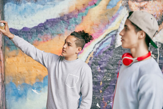Teenage boys spray painting on wall