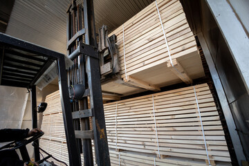 A diesel forklift loads freshly sawn pine logs, girders, bars, beams, bars, boards into a drying chamber. Industrial technology of wood production. - 633077169