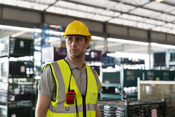 Portrait of male warehouse worker standing and wearing safety uniform and helmet in packaging department at warehouse storage