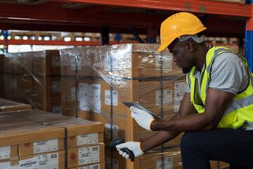 African American male warehouse worker scanning barcodes on boxes on shelf pallet in the storage...