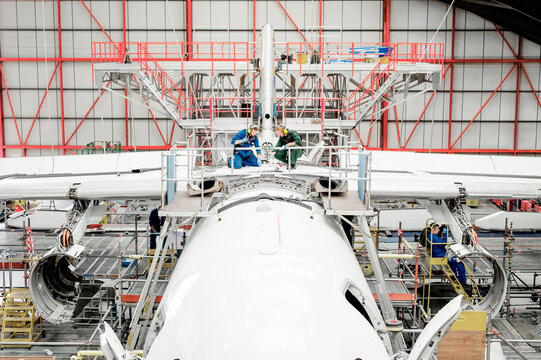 Workers on airplane in hangar