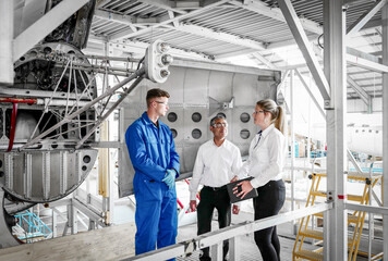 Workers with digital tablet in airplane hangar