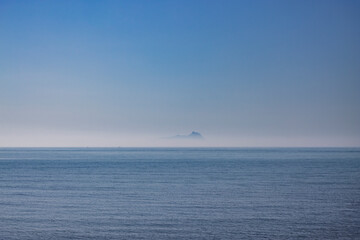 Obraz premium Ponza, Italy. The silhouette of the island emerging from the fog, seen from the Lazio coast in the distance.